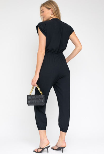 Collab Boutique black polyester dolman short sleeve button up jumpsuit with elastic waist and cuffed ankles.