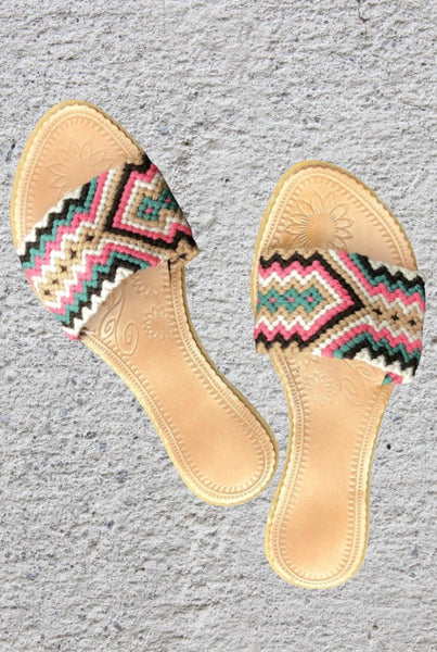 Collab Boutique handwoven slide sandals with colorful geometric pattern straps in coral, tan, brown, green, and ivory. Leather insole.