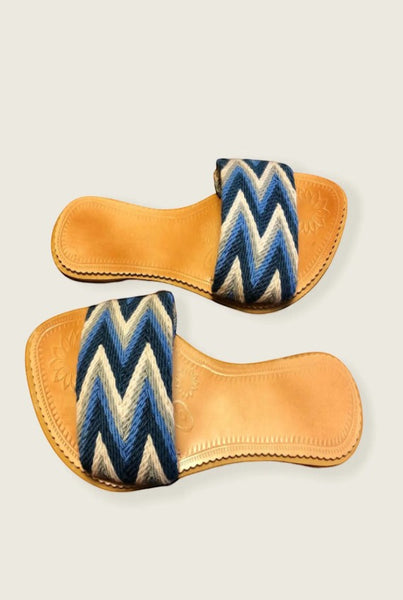Collab Boutique handwoven slide sandals with blue, grey, and white zig-zag pattern straps and leather insoles.