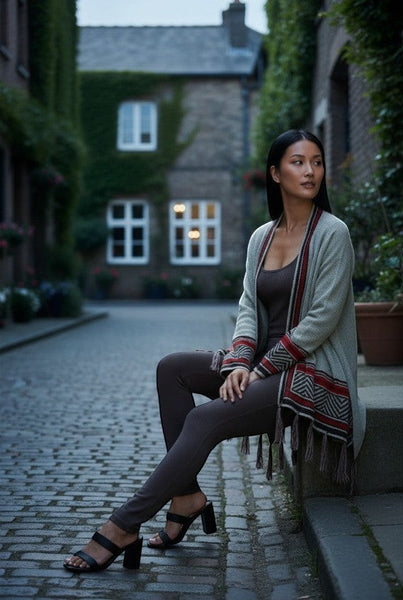 Collab Boutique light grey knit cardigan with geometric pattern and fringe on cuffs and hem, worn by a woman sitting outdoors.