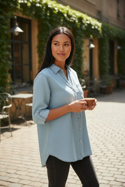 Collab Boutique light blue Tencel denim shirt with dolman sleeves and button cuffs, worn by a woman holding a coffee cup.