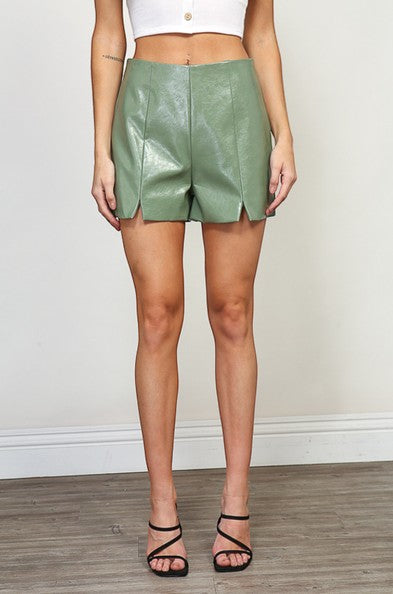 Collab Boutique sage green faux leather shorts with front hem slits and invisible zipper. Viscose blend.