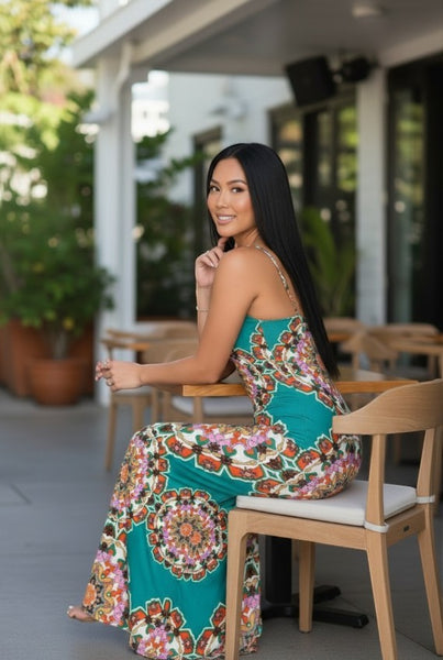 Collab Boutique teal geometric print maxi dress with adjustable straps and side slit, worn by a woman sitting at a table.